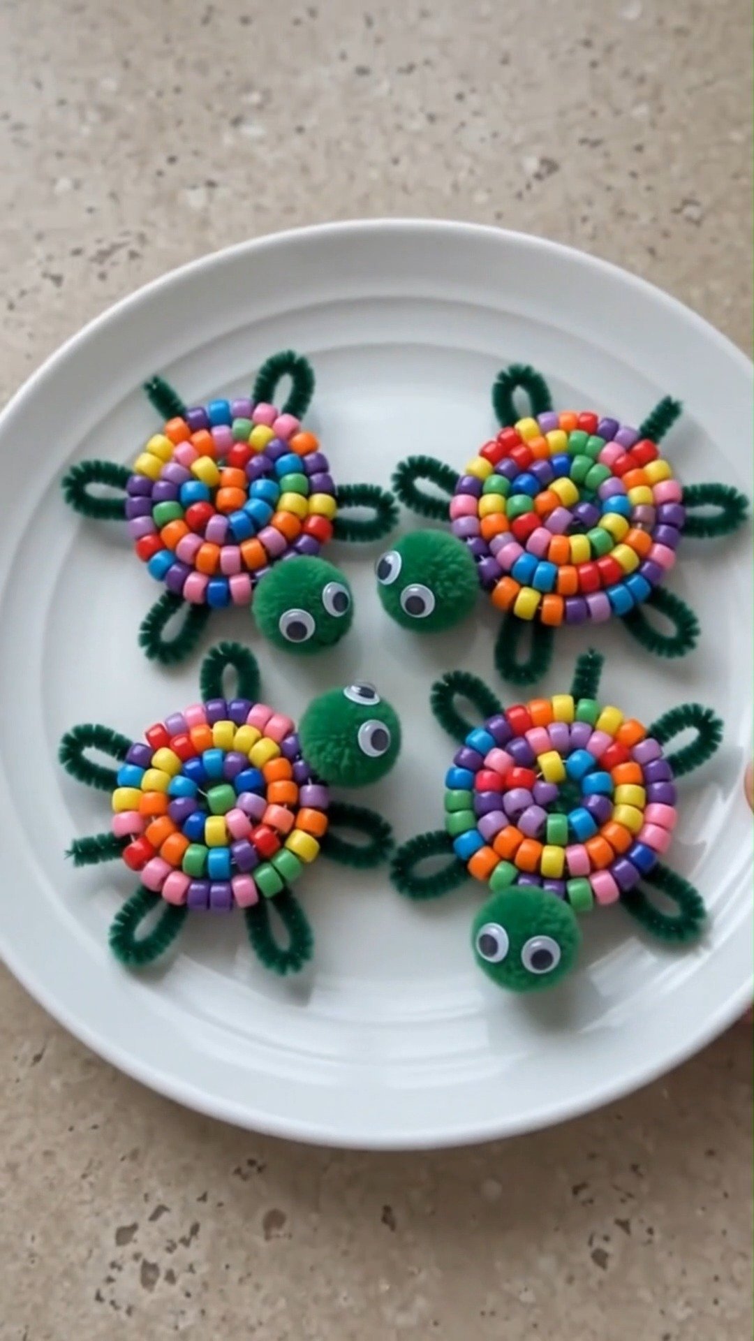 Bunte Pferdeschneiderperlen, dunkelgrüne Pompomreiniger, Pompons und Wackelaugen kommen zusammen, um bezaubernde kleine Schildkröten zu basteln, die perfekt für fantasievolles Spiel sind.