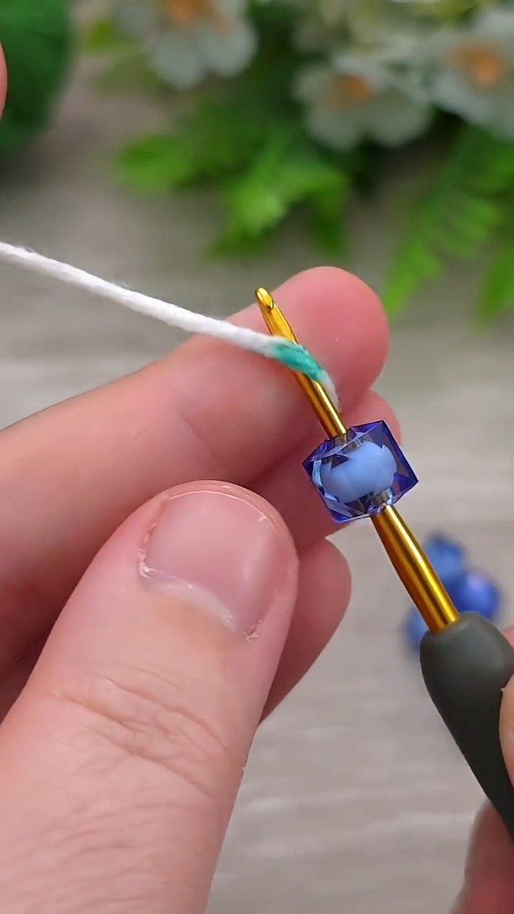 Hast du schon einmal mit Glaskristallperlen gehäkelt? 💎 Sieh dir an, wie das Auffädeln von Perlen direkt auf dein Garn dieses wunderschöne florale Zentrum erschafft!