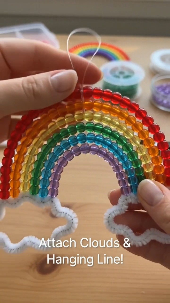 Bunte Perlen und sanfte Wolken vereinen sich zu einer fröhlichen Regenbogenhänge-Dekoration, die perfekt ist, um einen Raum aufzuhellen.